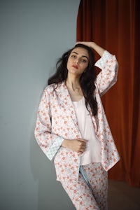 a woman is posing in a pink floral pajama set
