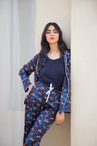 a woman in a blue pyjama set leaning against a wall
