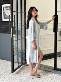 a woman in a blue robe standing in front of a door