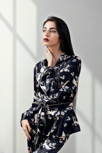 a woman is posing in a black silk pajama set